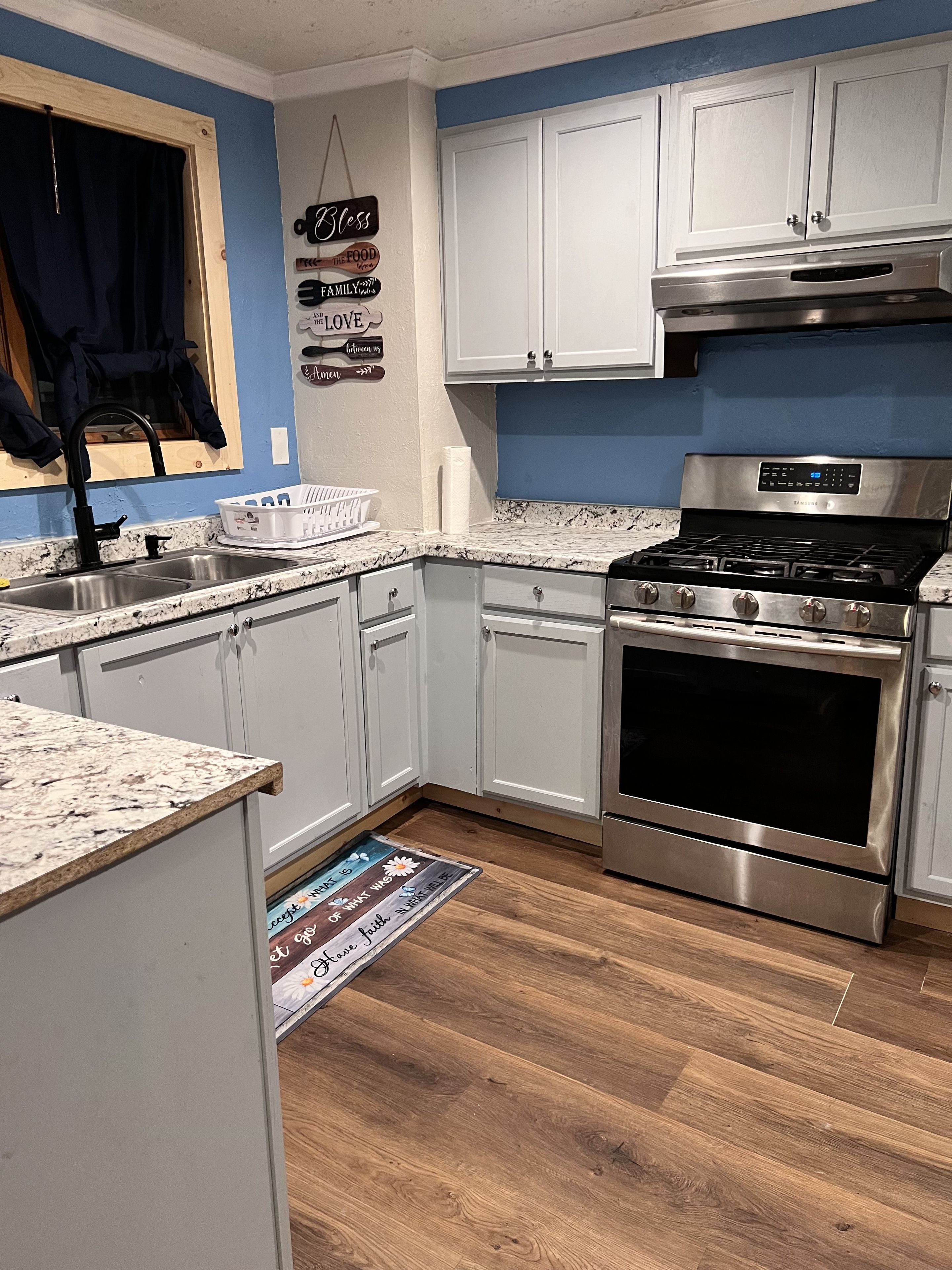 A modern kitchen with white cabinets, a stainless steel stove, and a wooden floor.