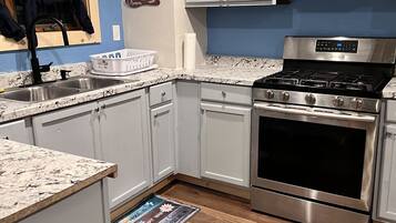 A modern kitchen with white cabinets, a stainless steel stove, and a wooden floor.