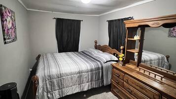 A bedroom with a bed, dresser, mirror, and a single wall decoration.