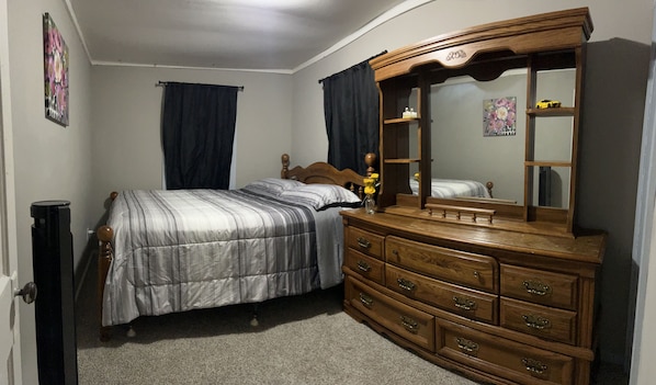 A bedroom with a bed, a dresser, a mirror, and a nightstand.