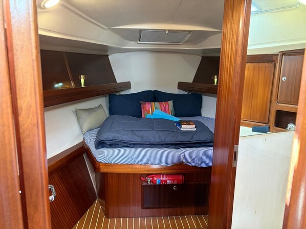 A compact cabin with a bed, pillows, and a small shelf with books.