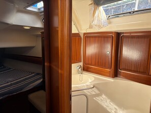 A compact cabin with a bunk bed, a small sink, and wooden cabinetry.