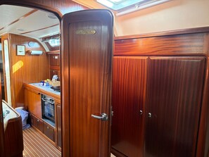 A wooden interior with a captain's door, a kitchenette, and a small galley area.