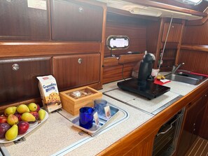 A kitchenette with a coffee maker, a sink, and a wooden cabinet.