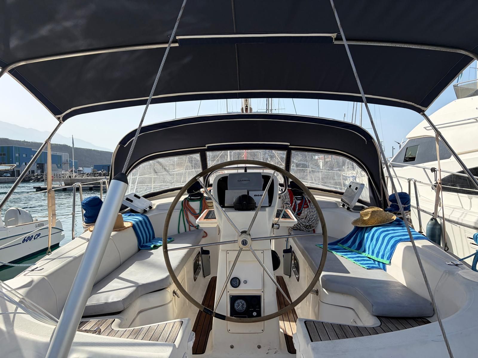 A boat's deck with a steering wheel, a Garmin device, and a B&G control panel.