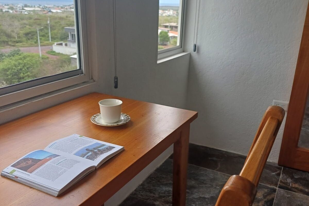 A corner room with a wooden table, a chair, a cup, and a magazine.
