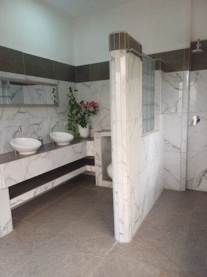 Un baño moderno con dos lavamanos, ducha y zona de ducha con mampara de cristal.