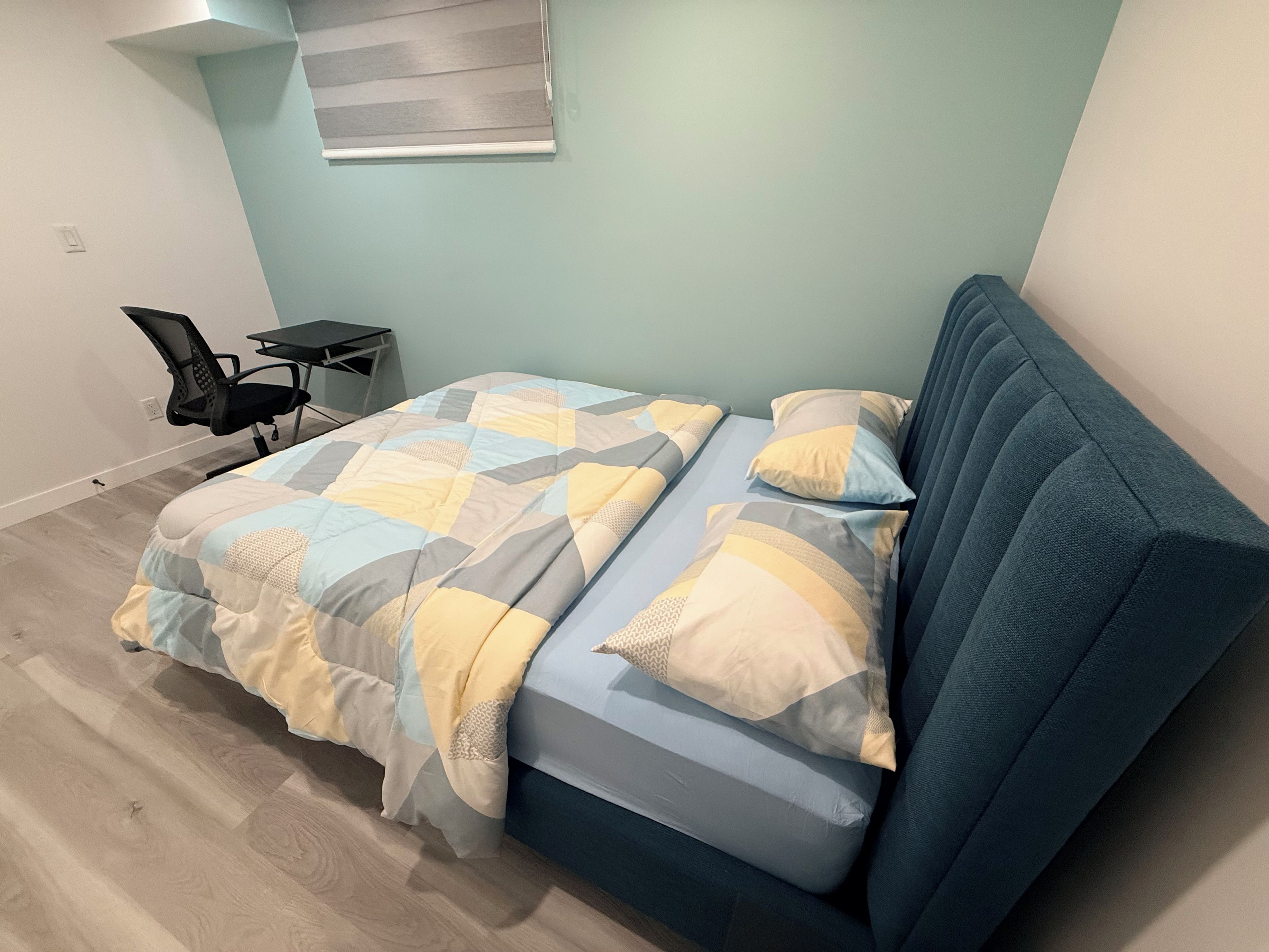 A bedroom with a bed, a chair, and a small table.