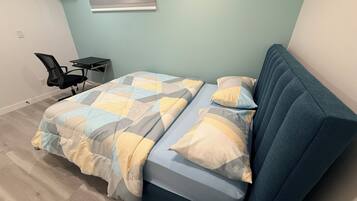 A bedroom with a bed, a chair, and a small table.