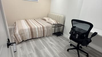 A bedroom with a bed, a desk, and a chair.