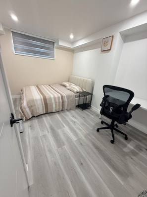 A bedroom with a bed, a desk, and a chair.