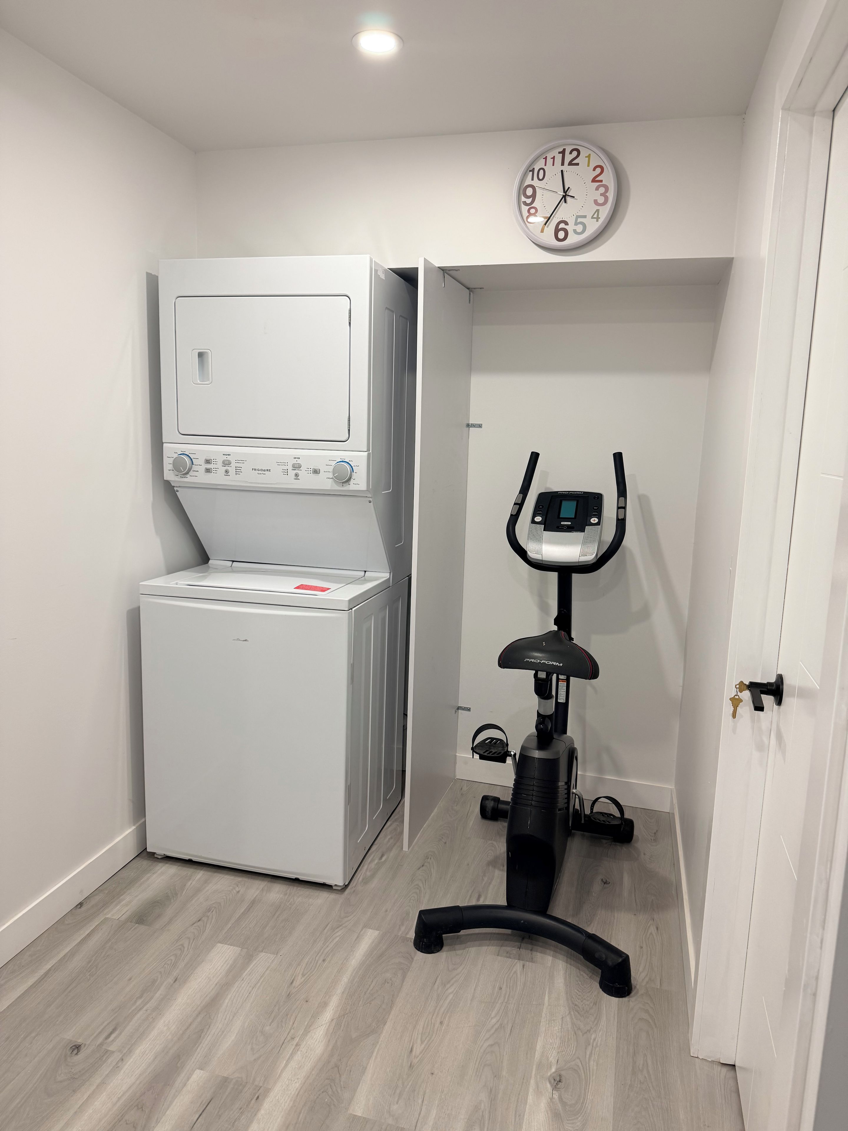 Ein Waschraum mit einer Waschmaschine und einem stationären Ergometer.