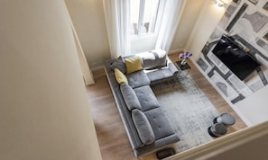 A modern living room with a grey sectional sofa, a small side table, and a patterned rug. - PORTA ROSSA EXCLUSIVE – ELEGANT FLORENCE APARTMENT WITH BALCONIES (Firenze)