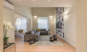 A modern living room with a sofa, a coffee table, and a TV mounted on the wall. - PORTA ROSSA EXCLUSIVE – ELEGANT FLORENCE APARTMENT WITH BALCONIES (Firenze)