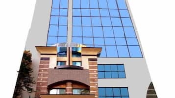 Un bâtiment moderne doté d’une façade en verre remarquable, d’une base en briques et d’une voiture garée devant.