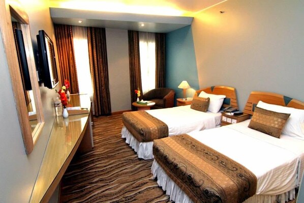 A hotel room with two beds, a desk, a chair, a mirror, and a television.