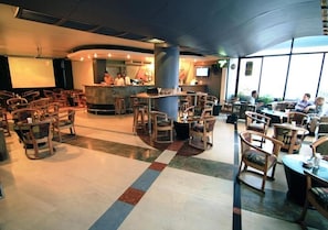 A spacious indoor area with multiple seating arrangements, a bar counter, and a projection screen.