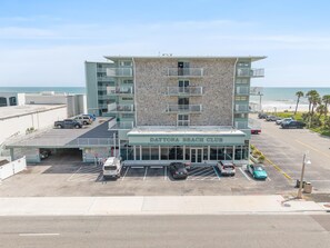 Ein mehrgeschossiges Gebäude mit einer Sandsteinfassade und Balkonen, namens Daytona Beach Club, mit einem Parkplatz davor.