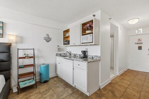 Uma cozinha compacta com armários brancos, micro-ondas e cafeteira.