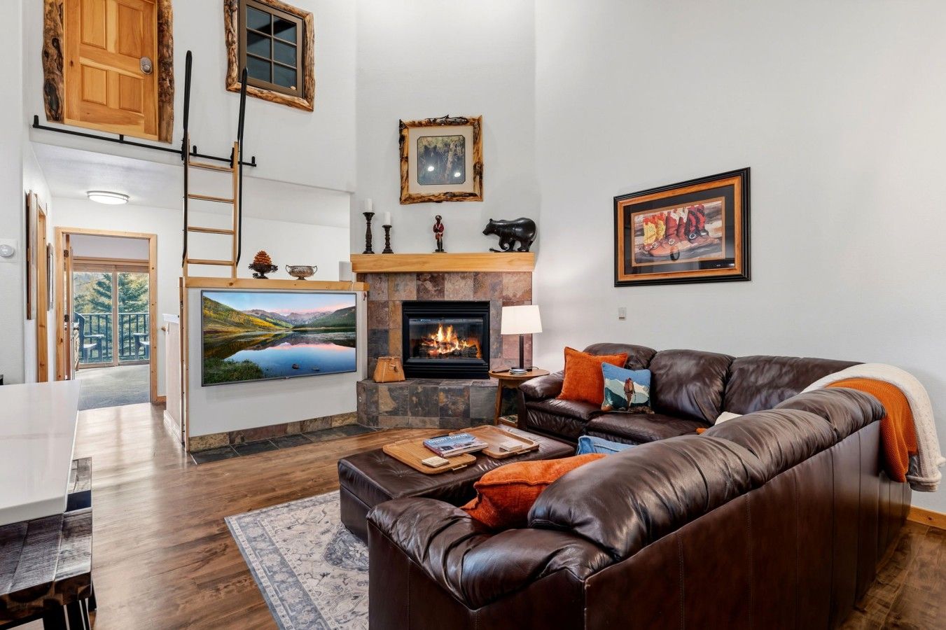 A living room with a fireplace, leather sofa, and a painting of a landscape.