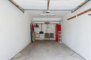 A garage with a concrete floor, a red door, and various items like a ladder, chairs, and a shelf. - Spacious Breckenridge Townhome, Community Hot Tub (Breckenridge)