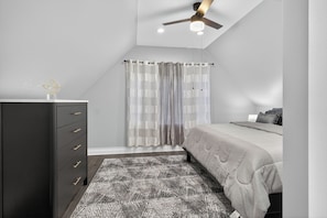 A bedroom with a bed, a dresser, a ceiling fan, and a patterned rug. - Emerald Point Family Home - 3BR/2BA with Garage (Chicago)
