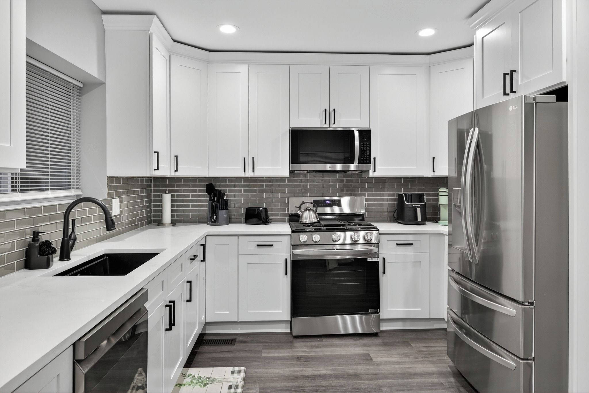 A modern kitchen with white cabinets, stainless steel appliances, and a tiled backsplash.