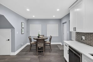 A modern kitchen with white cabinets, a dining table with chairs, and a built-in oven. - Emerald Point Family Home - 3BR/2BA with Garage (Chicago)