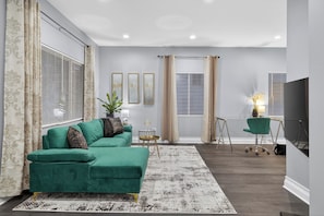 A living room with a sectional sofa, a coffee table, a TV, and a plant. - Emerald Point Family Home - 3BR/2BA with Garage (Chicago)