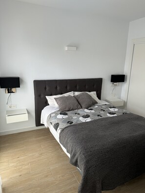 A bedroom with a dark headboard, a bed with patterned bedding, two bedside tables with lamps, and a white bedside drawer. - Villa With Pool Torrevieja (Torrevieja)