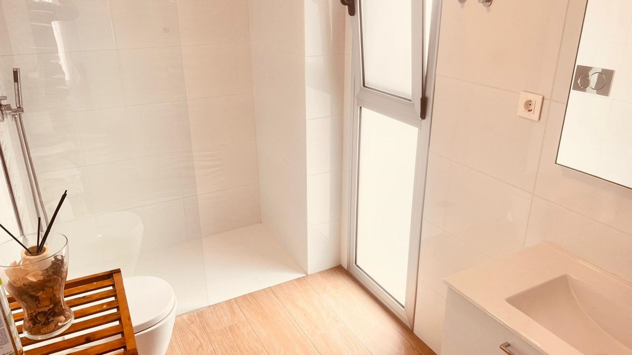 A modern bathroom with a glass shower enclosure, a white toilet, and a sink.