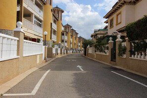 Eine Wohnstraße mit gelben Häusern, Balkonen und blauem Himmel.