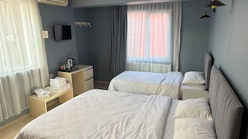Une chambre d’hôtel avec deux lits, un bureau, une chaise, une télévision et une fenêtre avec des rideaux.