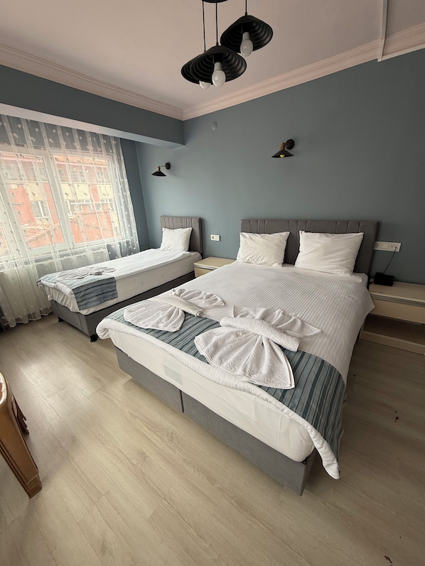 A hotel room with two beds, a large window, and a view of a building outside.