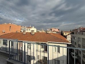 A residential area with terracotta-tiled roofs, balconies, and a clear sky.