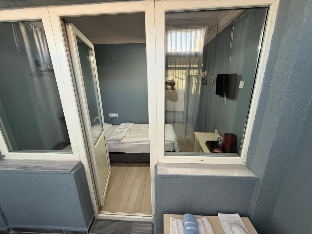 Una habitación pequeña con cama, una mesita y un espejo.