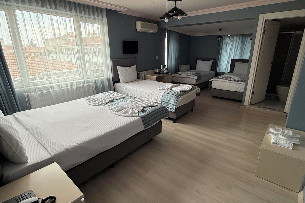 A hotel room with a large bed, a smaller bed, a desk, and a bathroom visible through an open door.