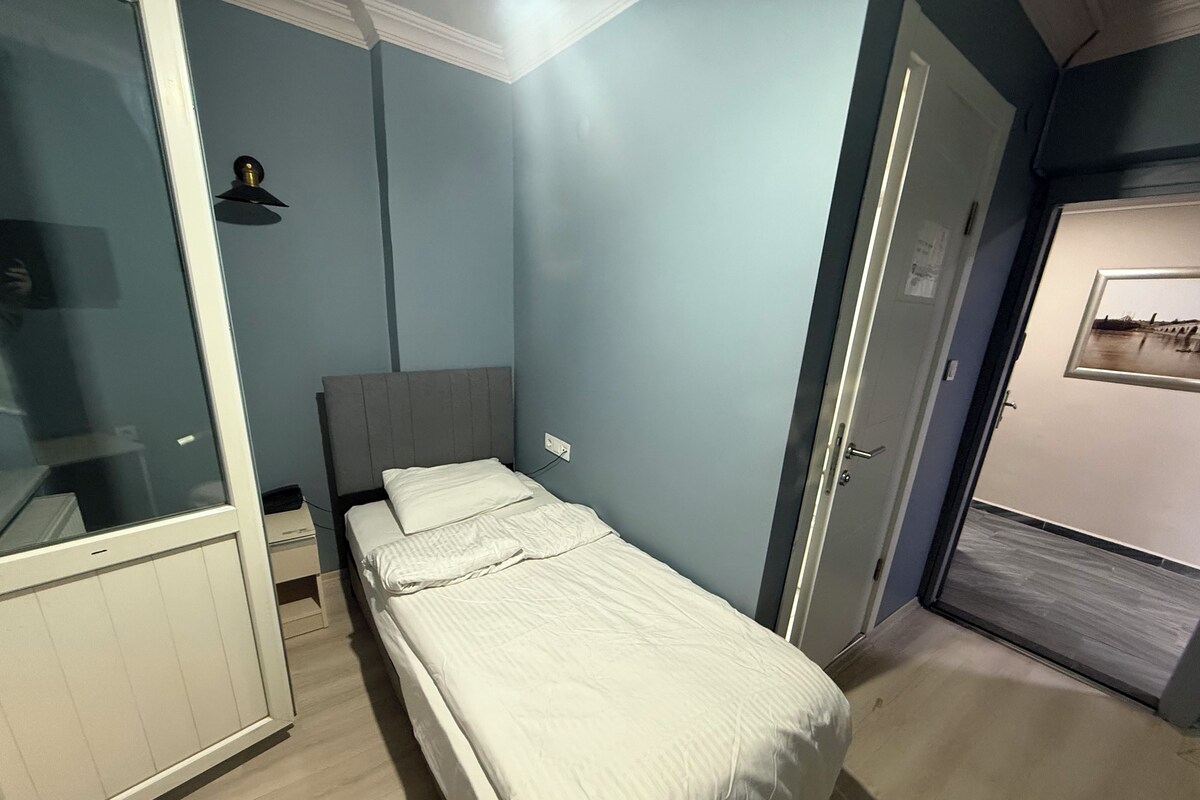 A bedroom with a bed, a wardrobe, and a door leading to another room.