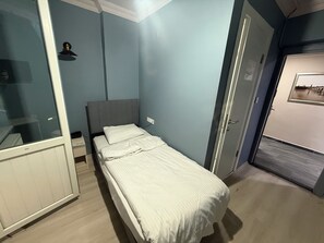 A bedroom with a bed, a wardrobe, and a door leading to another room.