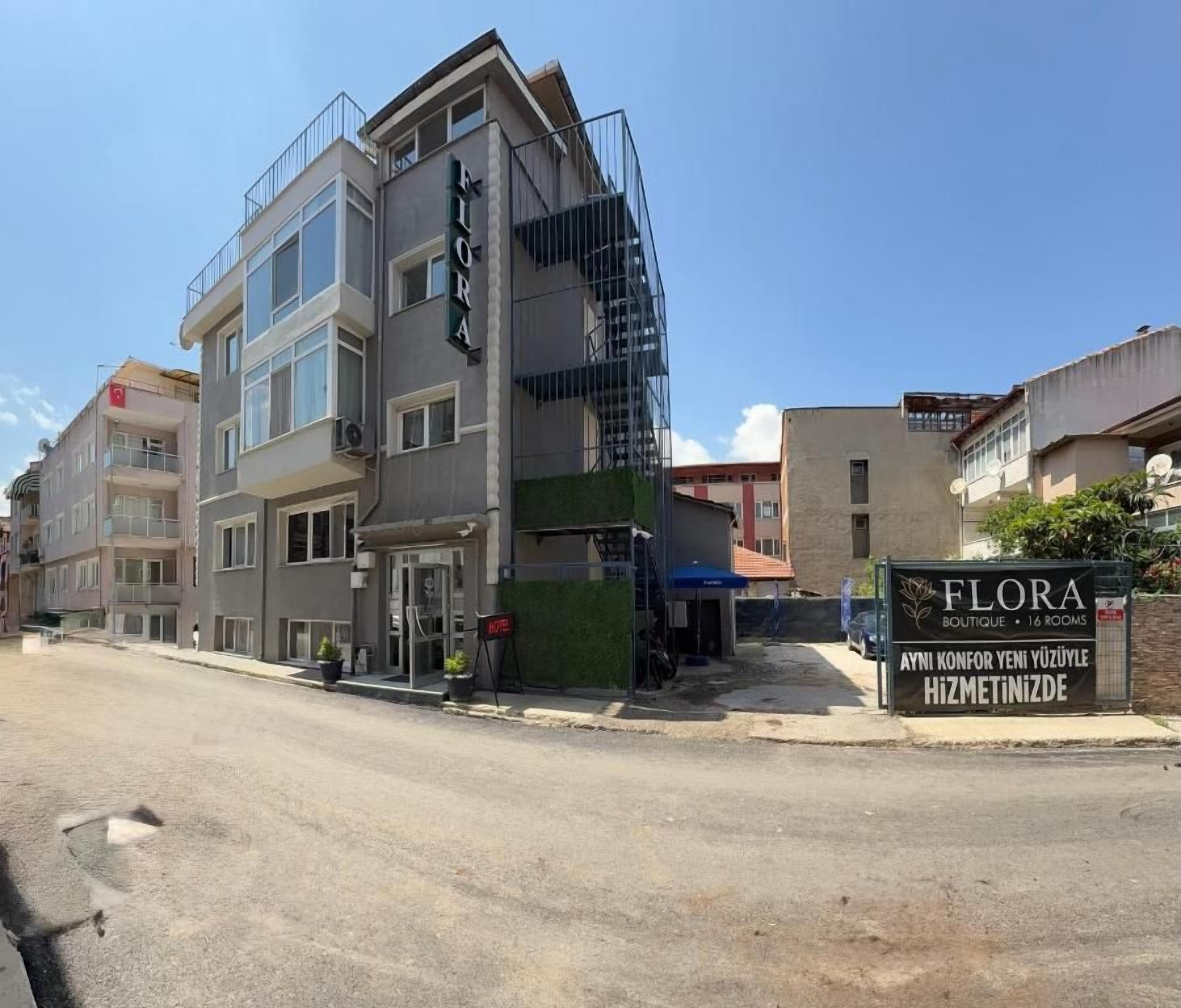 Un hotel de varios pisos con un letrero llamativo que dice 'FLORA BOUTIQUE 1 ROOM'.