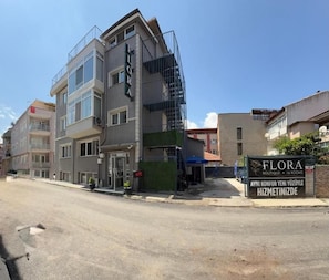 A multi-story hotel with a prominent sign for 'FLORA BOUTIQUE 1 ROOM'.