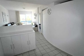 A modern, white interior with a kitchen area, a dining space, and a living area with a view. - Apartment Terrazas Playa Flamenca (Orihuela)