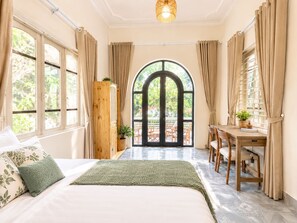 Een slaapkamer met een bed, een bureau en uitzicht op een terras.