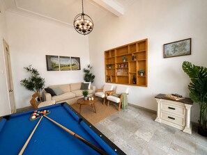 A living room with a pool table, sofas, a wooden shelf, and a painting. - West Lake Peaceful Villa by Anamoi (Hà Nội)