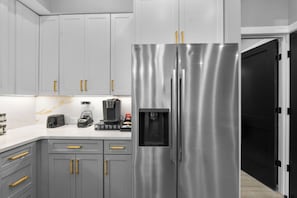 Una cocina moderna con gabinetes grises, electrodomésticos de acero inoxidable y un dispensador de agua.