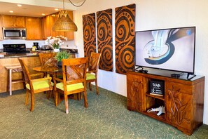 A hotel room with a dining area, a flat-screen TV, a minibar, and a decorative wall panel. - Ocean View Kaanapali Shores Spacious One Bedroom (Lahaina)