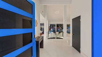 A modern interior with a blue door, a glass partition, and a dining area with white chairs.
