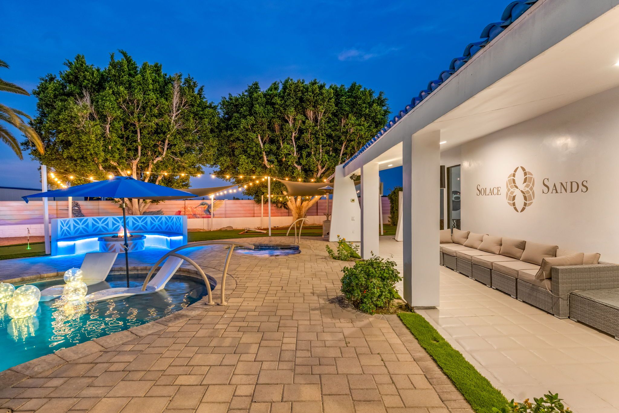 A pool area with a lounge chair, a small pool, and a covered seating area.