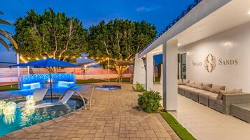 A pool area with a lounge chair, a small pool, and a covered seating area.