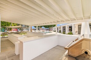 Un espace extérieur avec piscine, comprenant un coin salon couvert, un bar et une structure en bois.